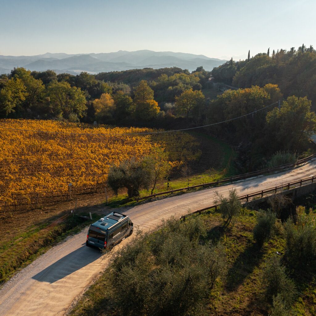 "Autocaravana en la carretera a través de los campos y bosques del Val d'Orcia al atardecer.