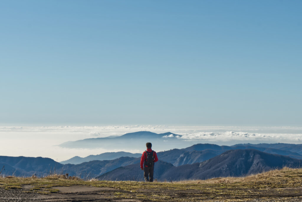 Persona in lontananza che guarda un ampio panorama montano