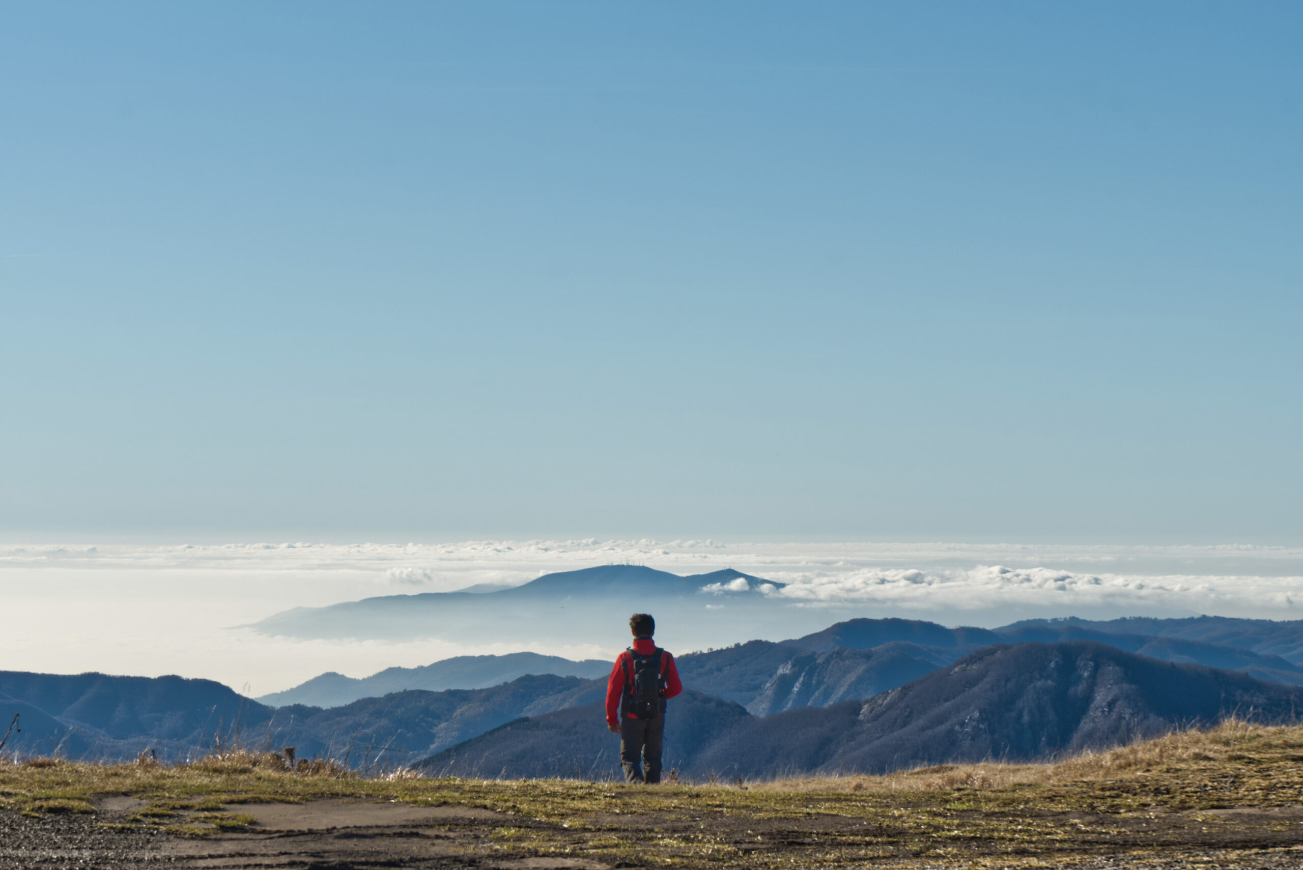 Persona in lontananza che guarda un ampio panorama montano