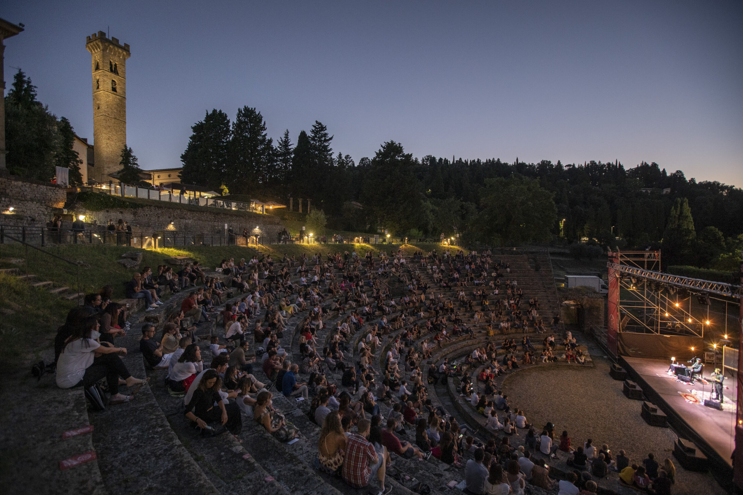 Pubblico sugli spalti del Teatro Romano di Fiesole durante un spettacolo in notturna