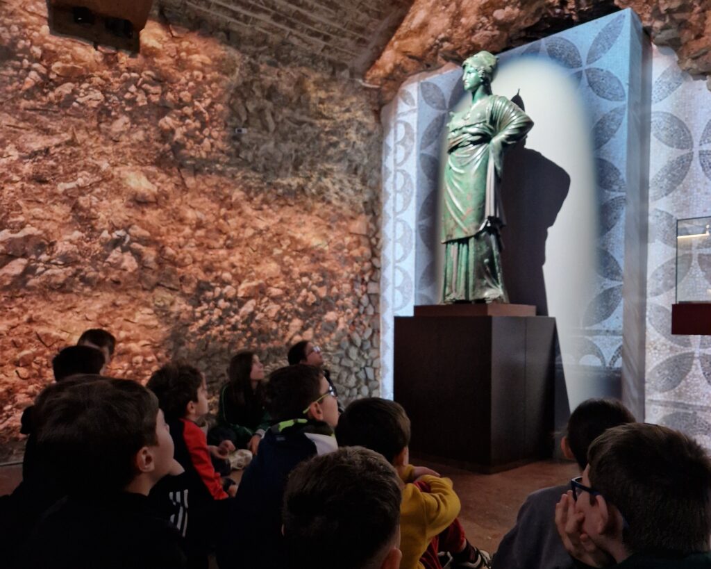 Nell'immagine, giovani studenti di spalle che guardano la statua della Minerva.