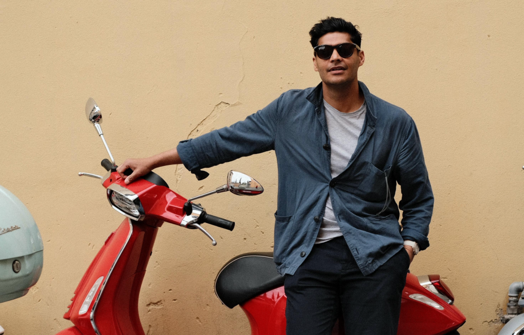 Ragazzo con occhiali da sole appoggiato a una Vespa