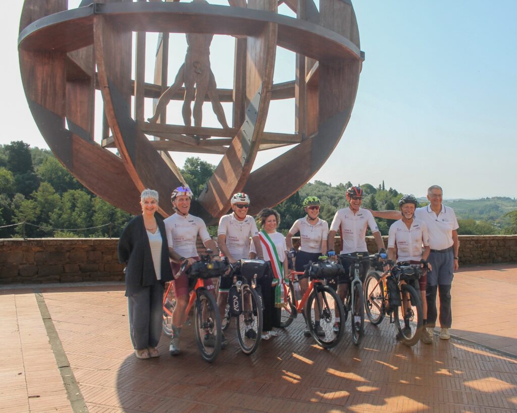 Immagine di grupppo dei partenti con le loro bici sotto il monumento a Leonardo