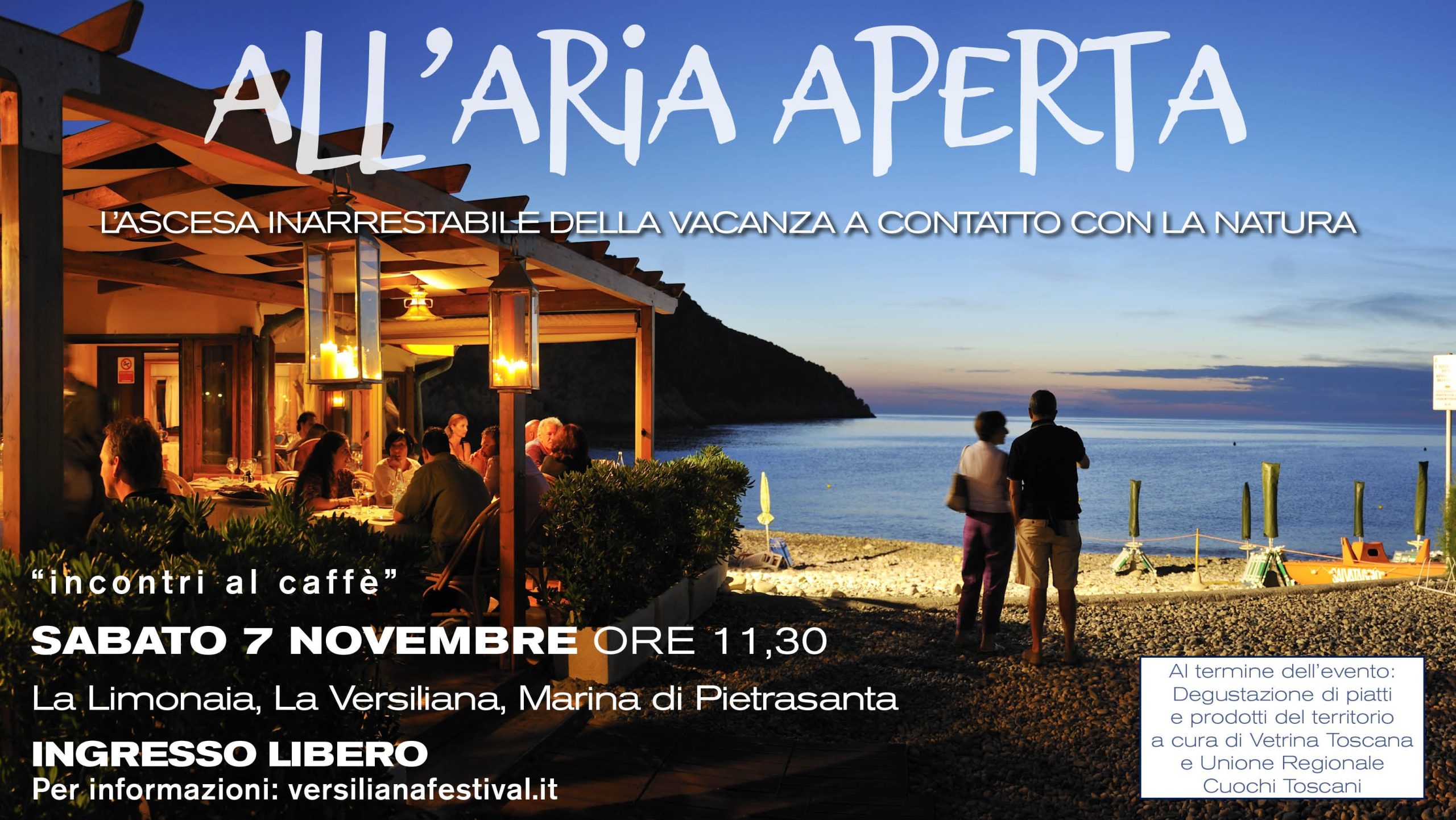 AriaAperta_1600x1052_WA Persone sedute in un bar all'aperto al tramnto sul mare, con altre due persone in piedi sulla spiaggia.